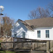 Alton schoolhouse in 2016 with a wooden ramp in front and windmill to the left 