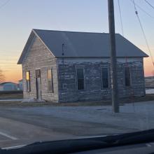 Unpainted schoolhouse during sunset