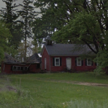 Red schoolhouse sitting amongst trees