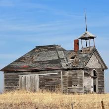 Wooden schoolhouse standing abandonded in a field