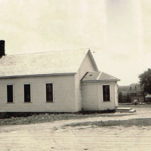 Photo of a white schoolhouse in a town