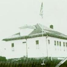 White schoolhouse with a flag