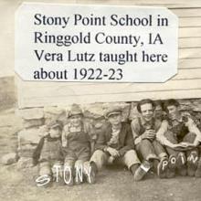 Children sitting outside the school with "Stony Point" written on the soles of their shoes. 