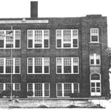 Photo of a three-story brick schoolhouse
